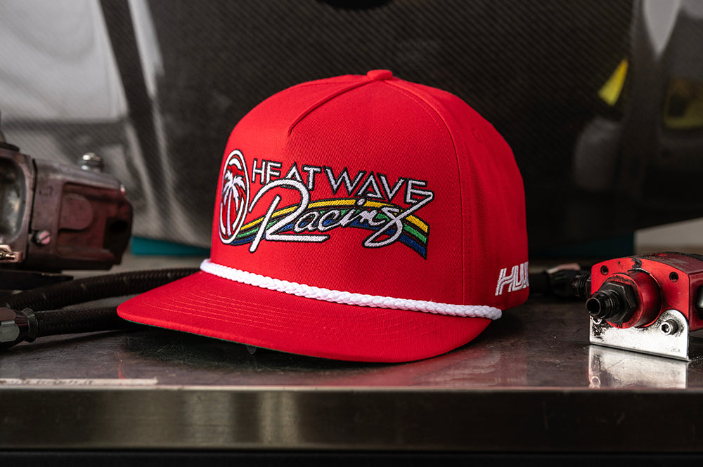 Lying on a bench is the Heat Wave Visual Trading Paint Red Hat.